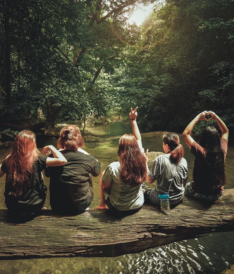Women sitting on a log by a mountain stream.