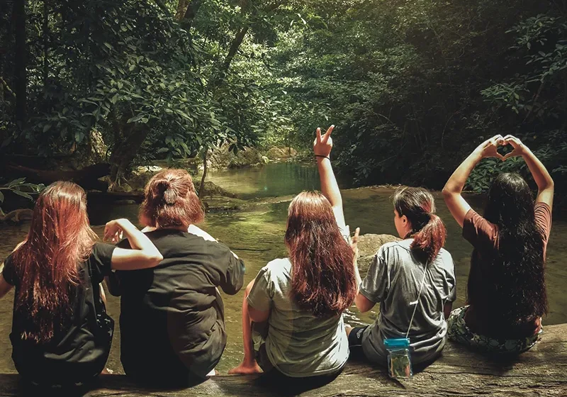 Women sitting on a log by a mountain stream.