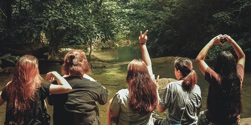 Women sitting on a log by a mountain stream.